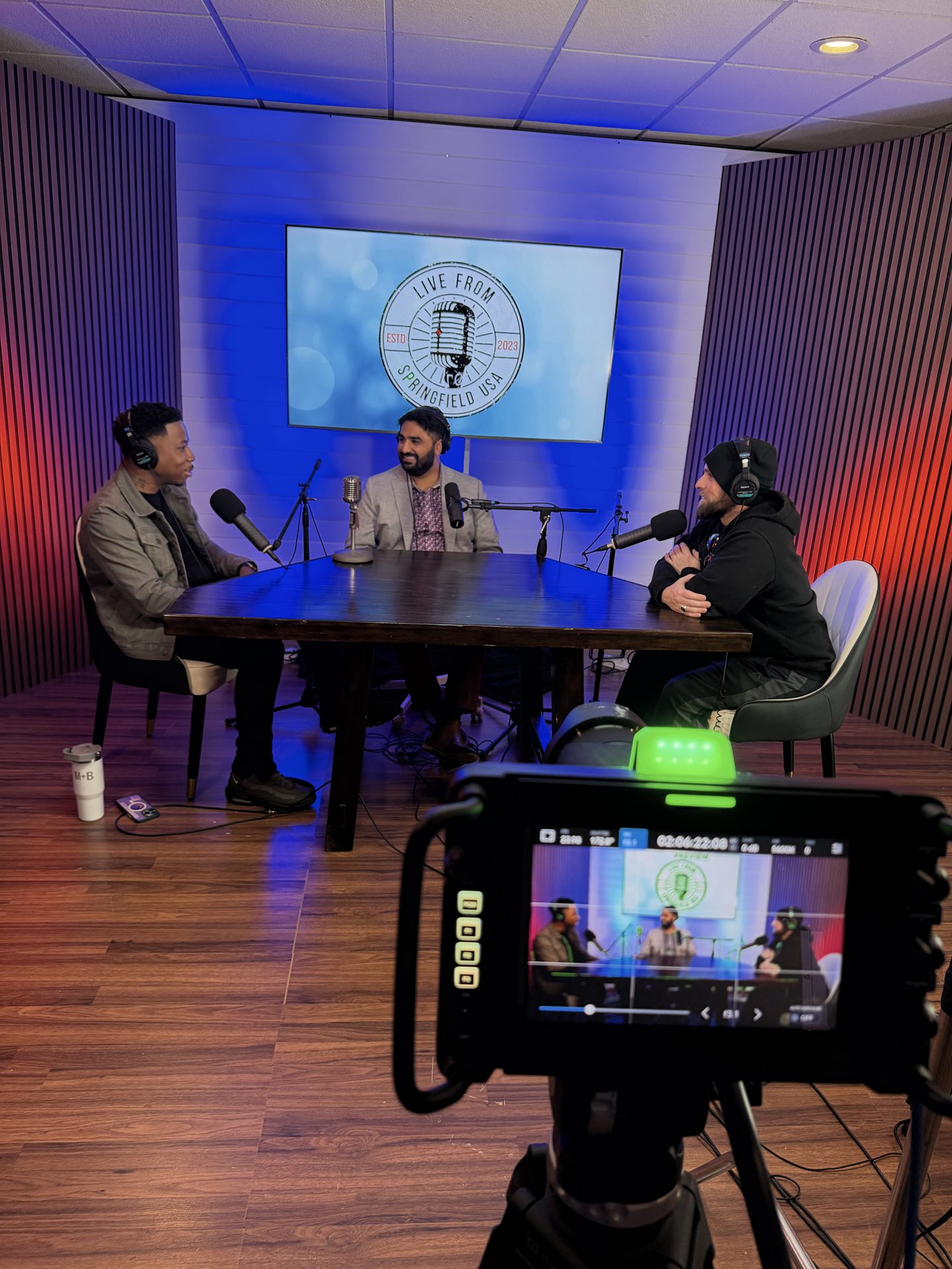 Behind-the-scenes view of a podcast recording with LUSA branding on backdrop