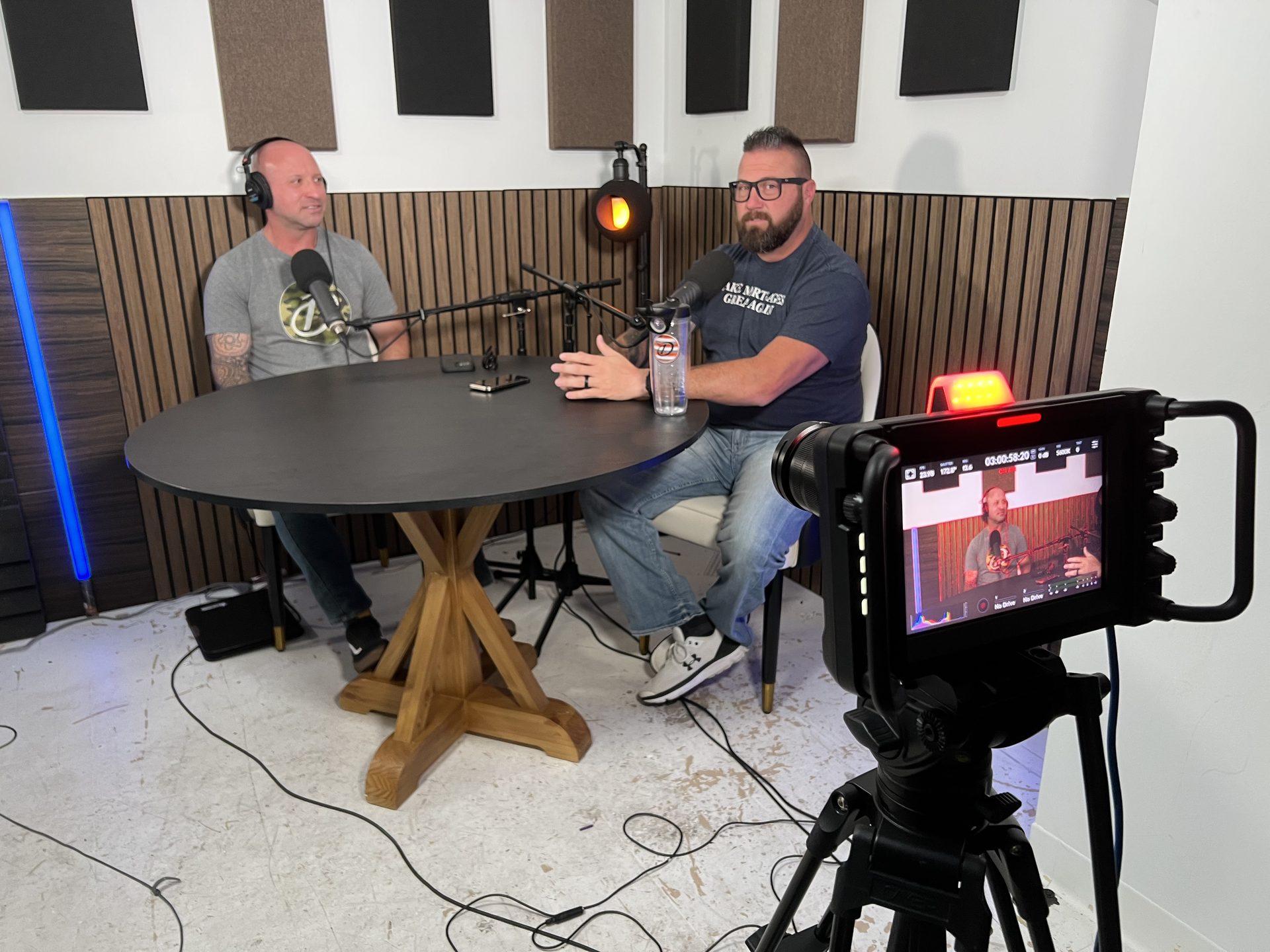 Two guests recording in the second podcast studio with camera monitor in foreground