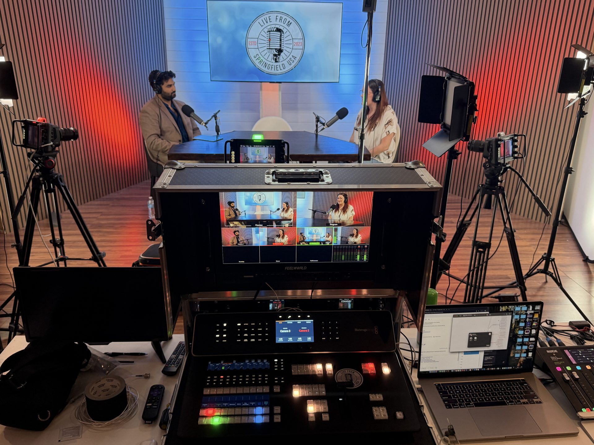 Full production setup with Blackmagic switcher and multi-cam monitoring at the podcast table